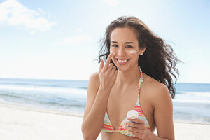 Mixed race woman applying sunscreen on beach